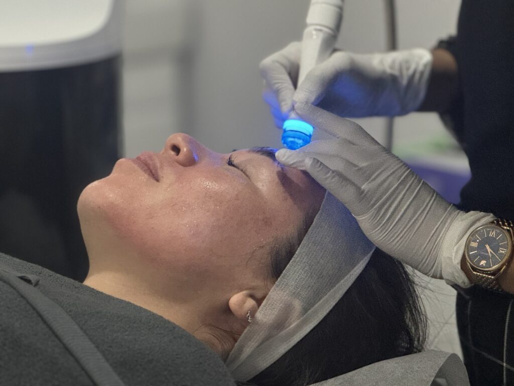 Client receiving a Hydrafacial from a gloved clinician